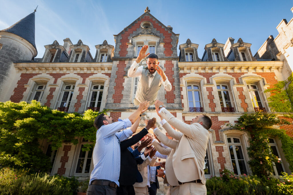 marié lancé en l'air devant la façade du château de la Pouyade