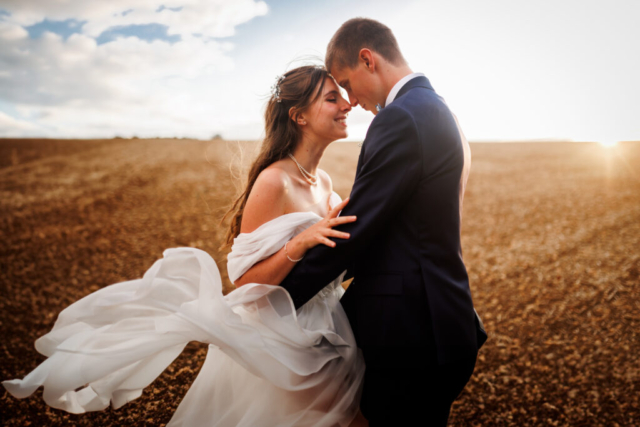 Photo de couple au coucher de soleil avec le vent dans la robe