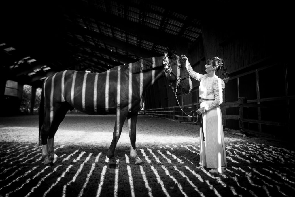 Belle photo de mariage d'une mariée avec son cheval zébré par la lumière