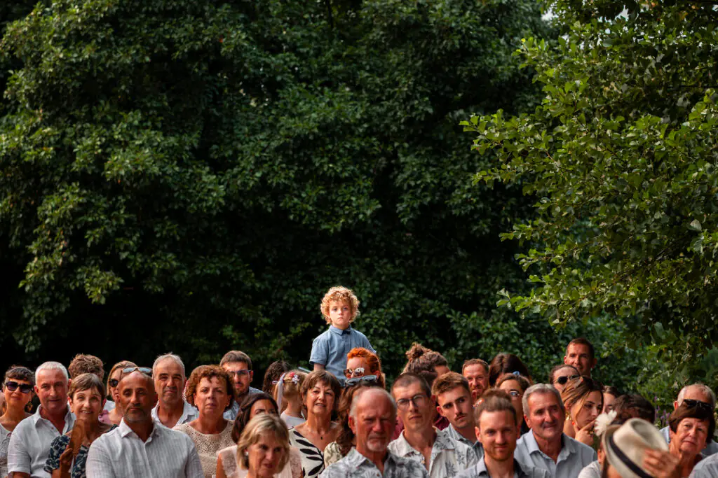 Sc&egrave;ne dr&ocirc;le et mignonne d'un enfant au dessus de tous les invit&eacute;s pour pouvoir regarder la c&eacute;r&eacute;monie la&iuml;que lors d'un mariage en Charente