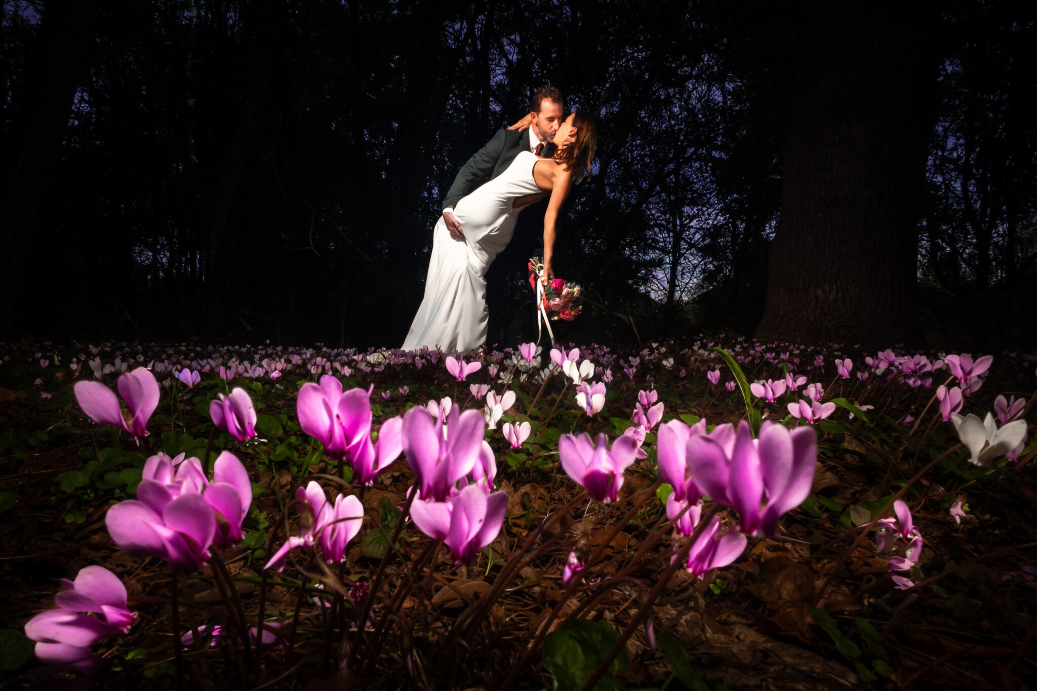 image d'un couple de marié photographié à leur mariage par Antoine OLLIER. Cette photo épique est prise au domaine de Bélisle en Charente. Le couple est au milieu des fleurs, des cyclamens sauvages
