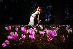 image d'un couple de marié photographié à leur mariage par Antoine OLLIER. Cette photo épique est prise au domaine de Bélisle en Charente. Le couple est au milieu des fleurs, des cyclamens sauvages