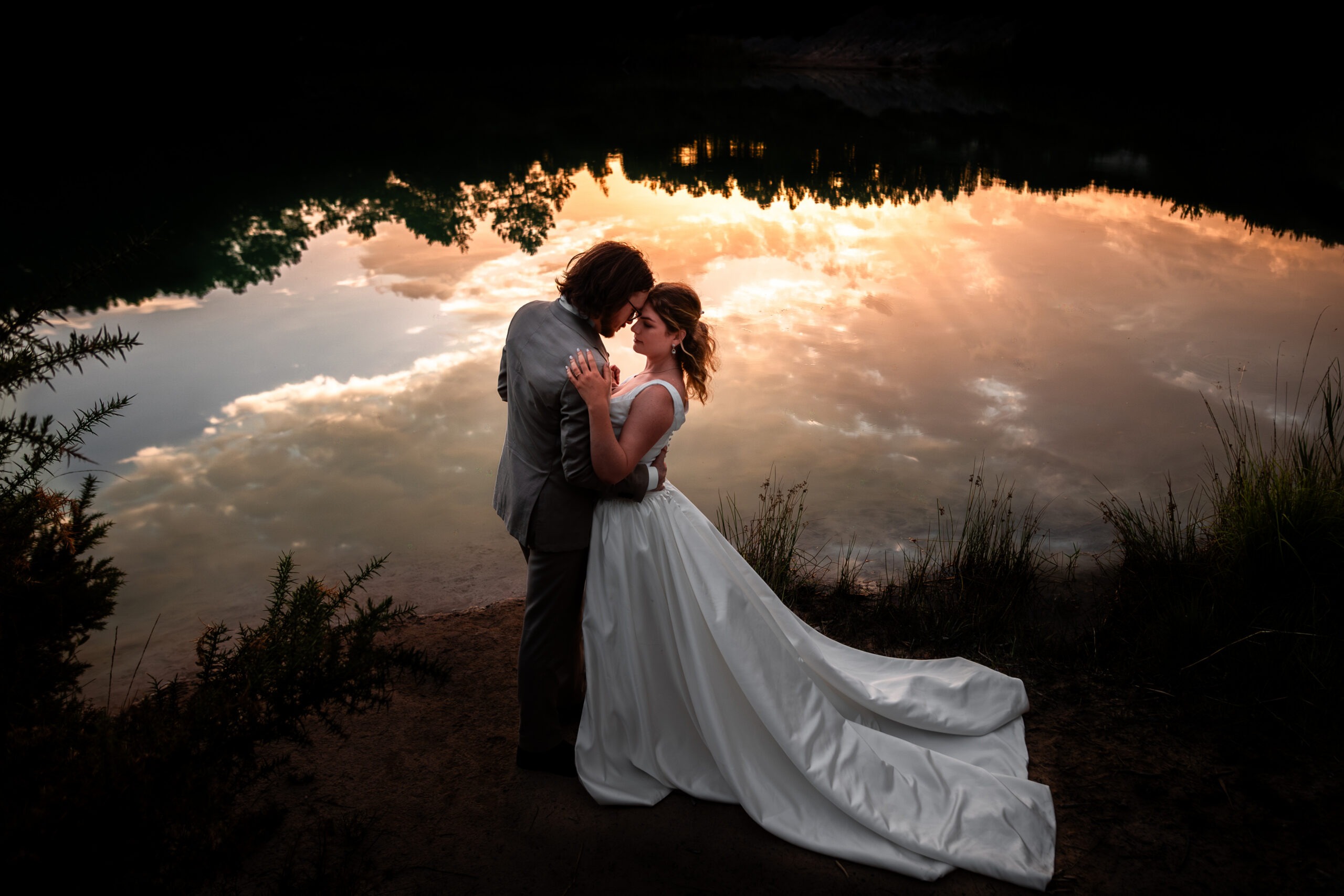 Couple de mariés lors d'une séance Day After en Charente après leur mariage en Charente. Image poétique, romantique d'un couple au bord d'un lac en Charente au coucher de soleil