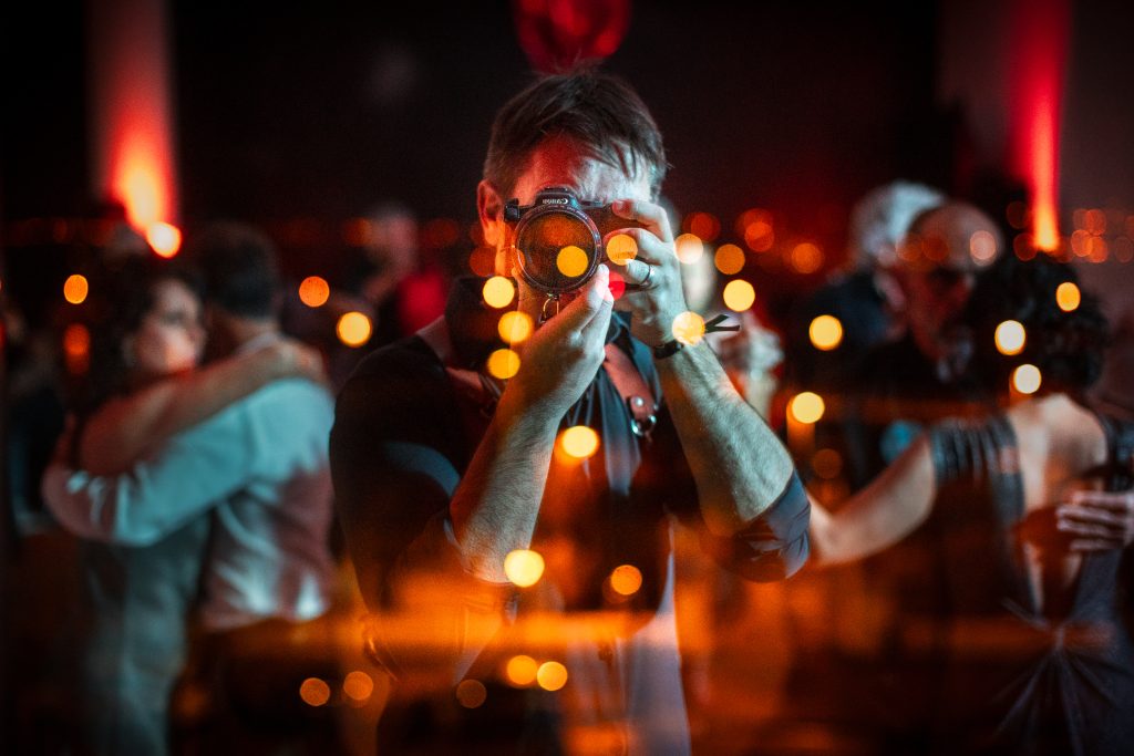 Autoportrait du photographe de mariage en Charente Antoine Ollier photo réalisée en Milonga de Tango dans le reflet de la vitre avec danseurs en arrière plan