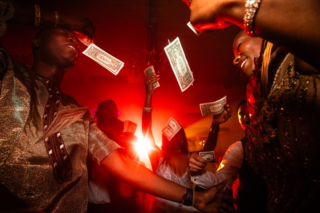 sc&egrave;ne de f&ecirc;te dans laquelle volent des billets de banque dans une ambiance de f&ecirc;te et de lumi&egrave;re rouge sur un mariage au ch&acirc;teau Gassies photo r&eacute;alis&eacute;e par Antoine OLLIER Photographe de mariage en Charente